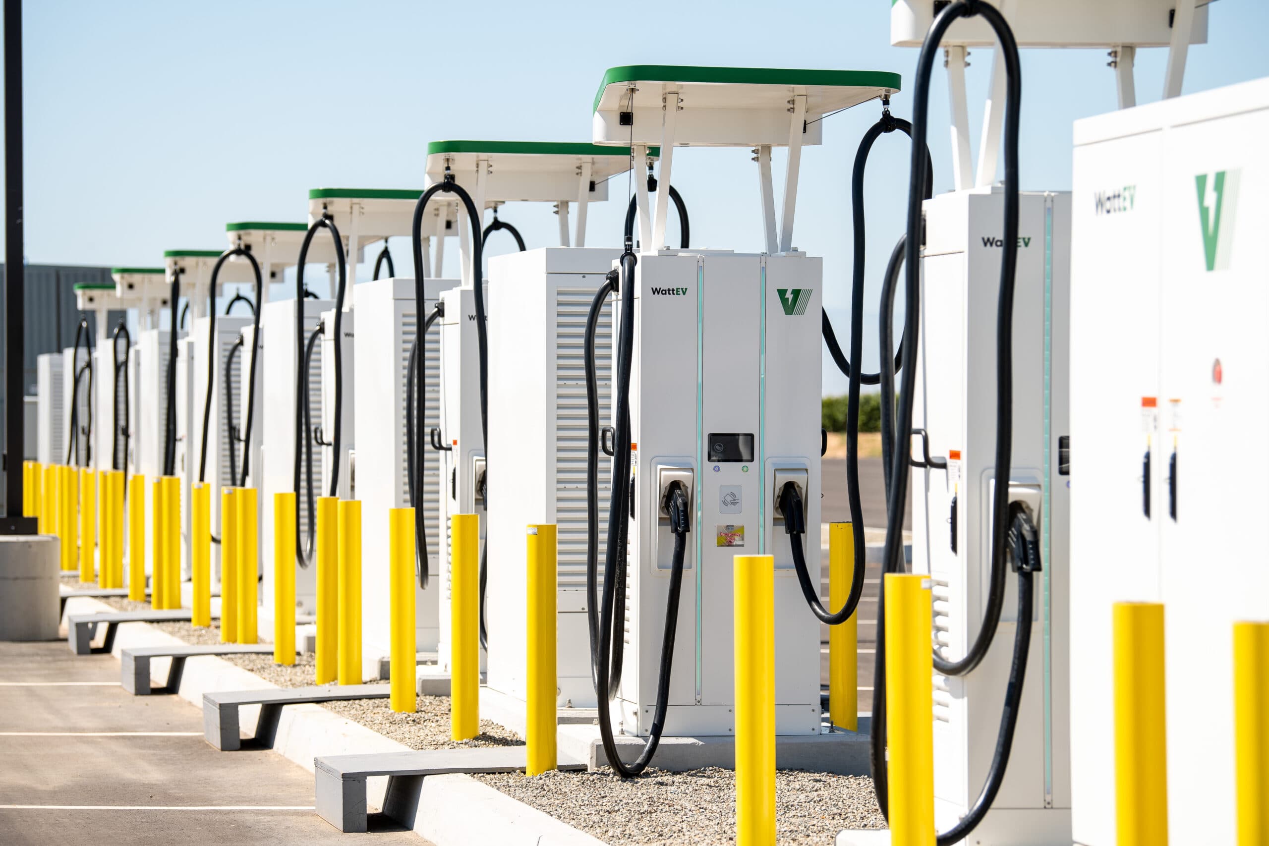 Electric Class 8 trucks charging at a WattEV megawatt depot near a major port.